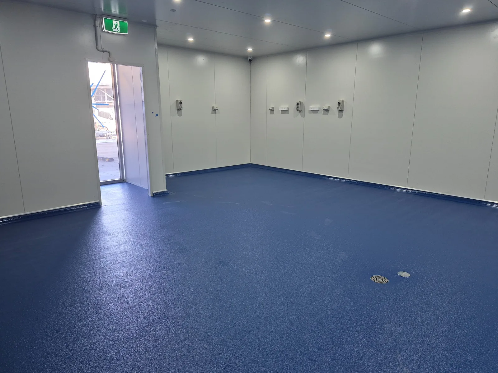 Blue coated floor in a commercial room with white panel walls