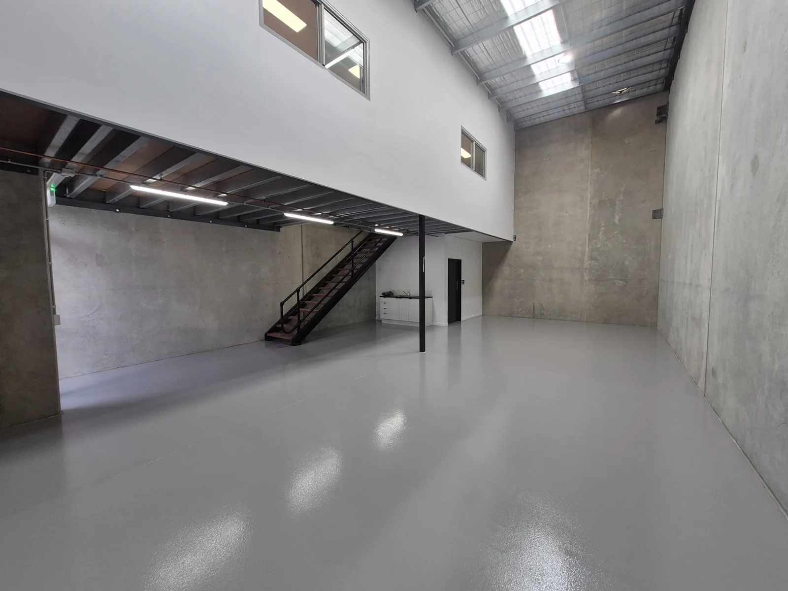 Grey coated warehouse floor beneath a steel mezzanine