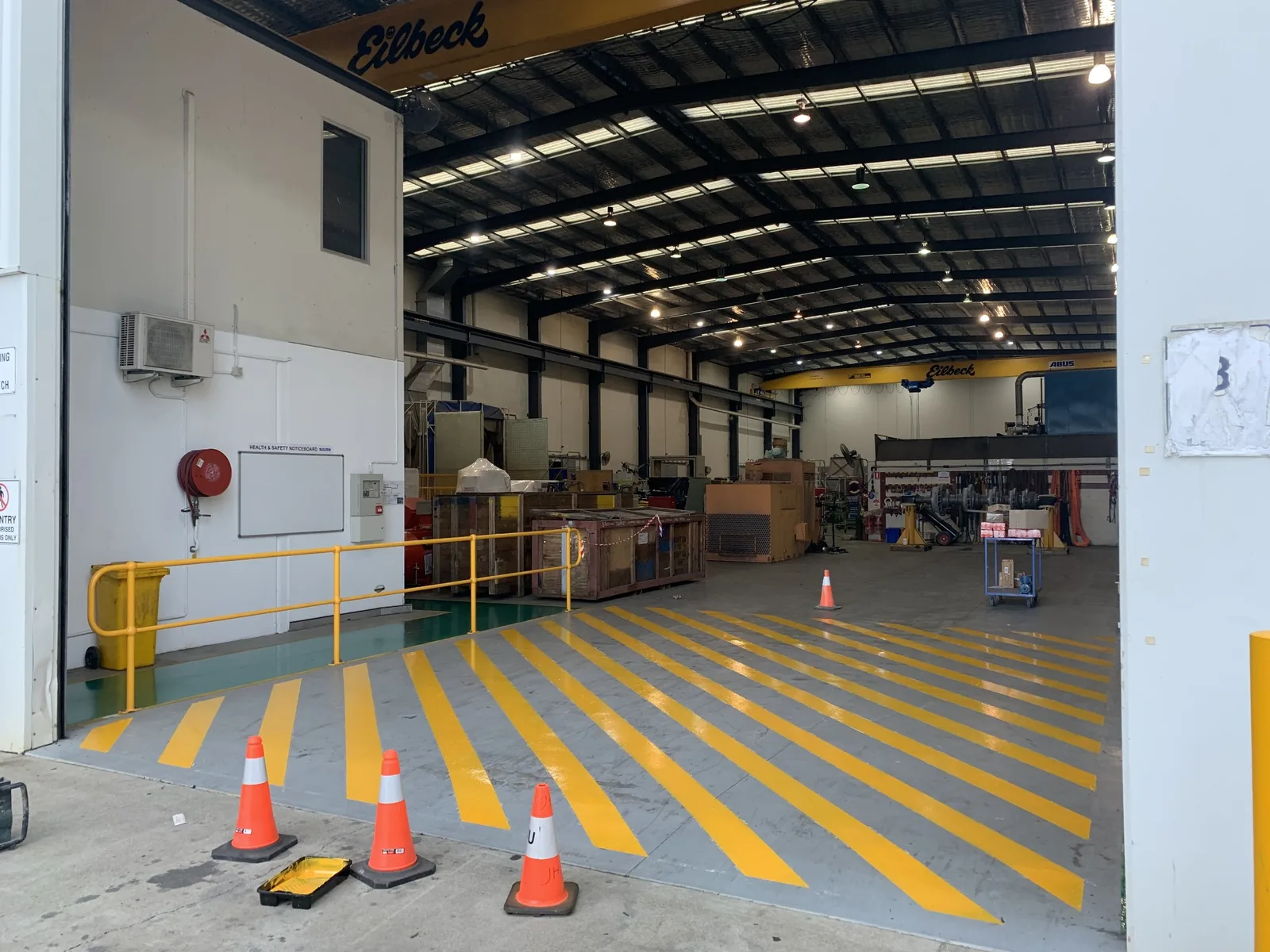 Industrial entrance with yellow floor markings and safety cones