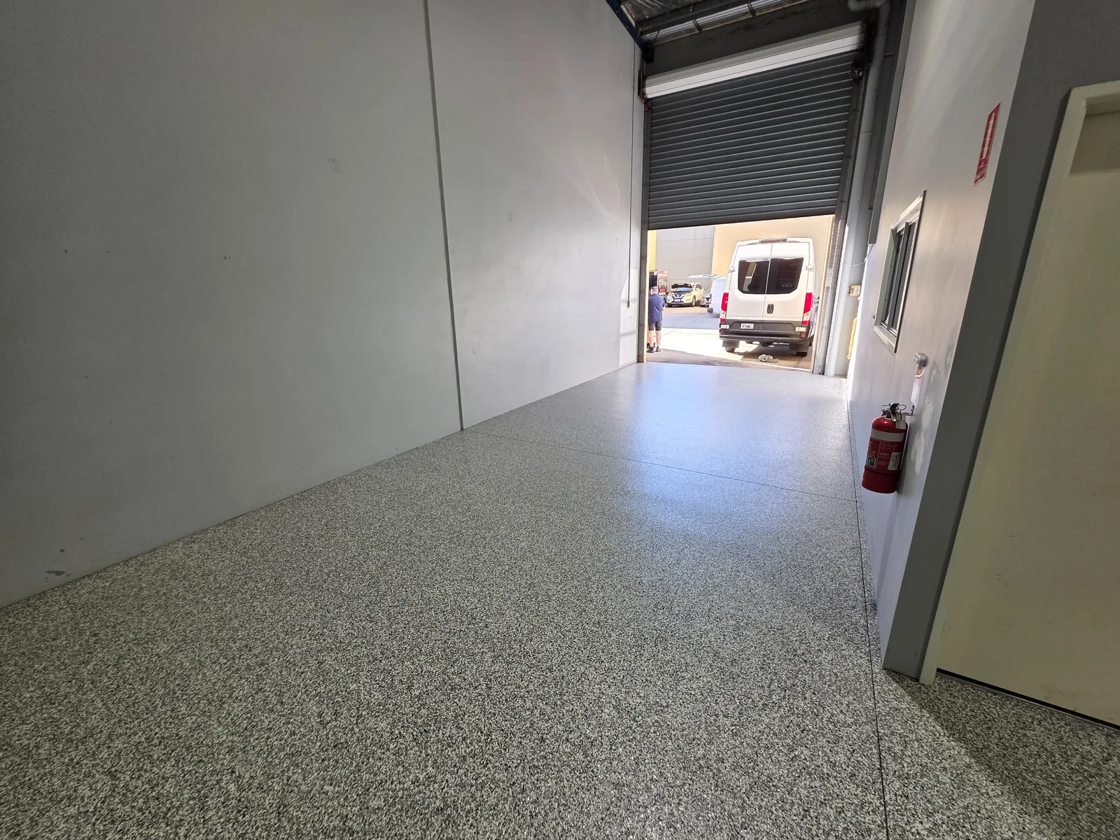 Speckled floor leading to an open roller door