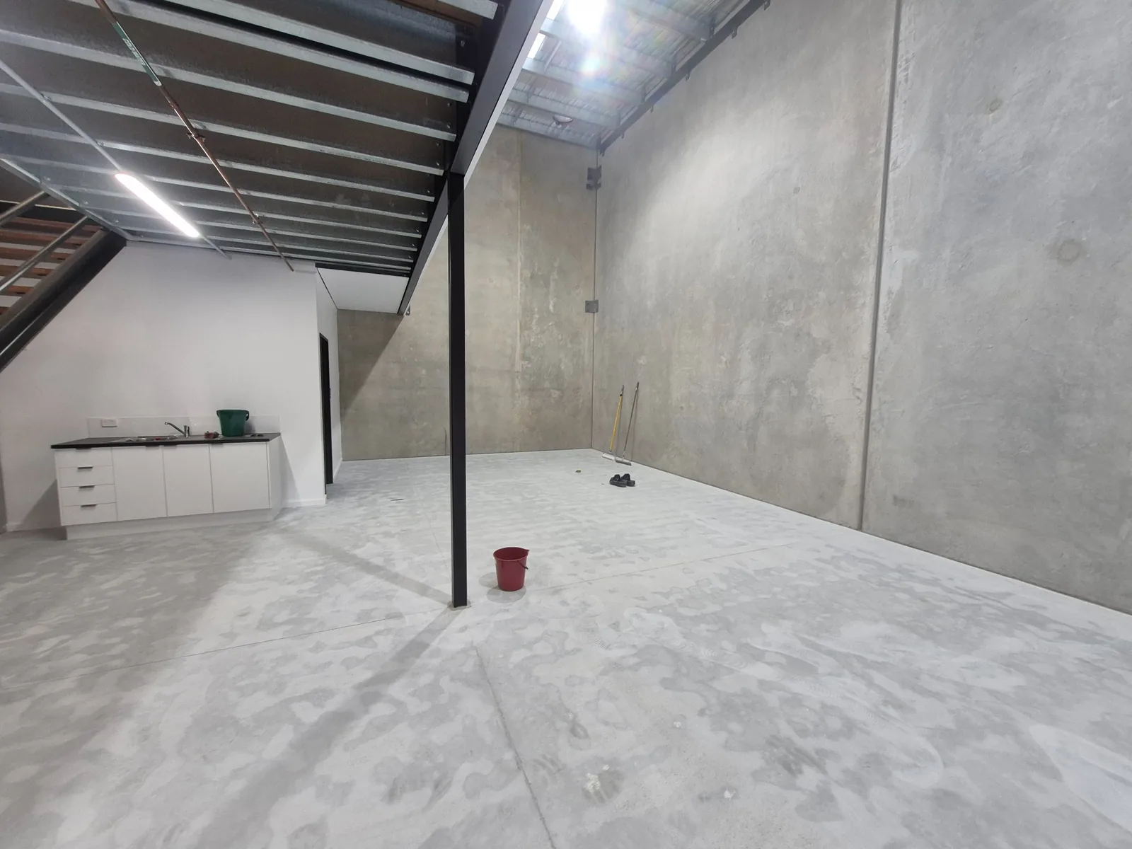 Prepared concrete floor inside a warehouse beneath a mezzanine